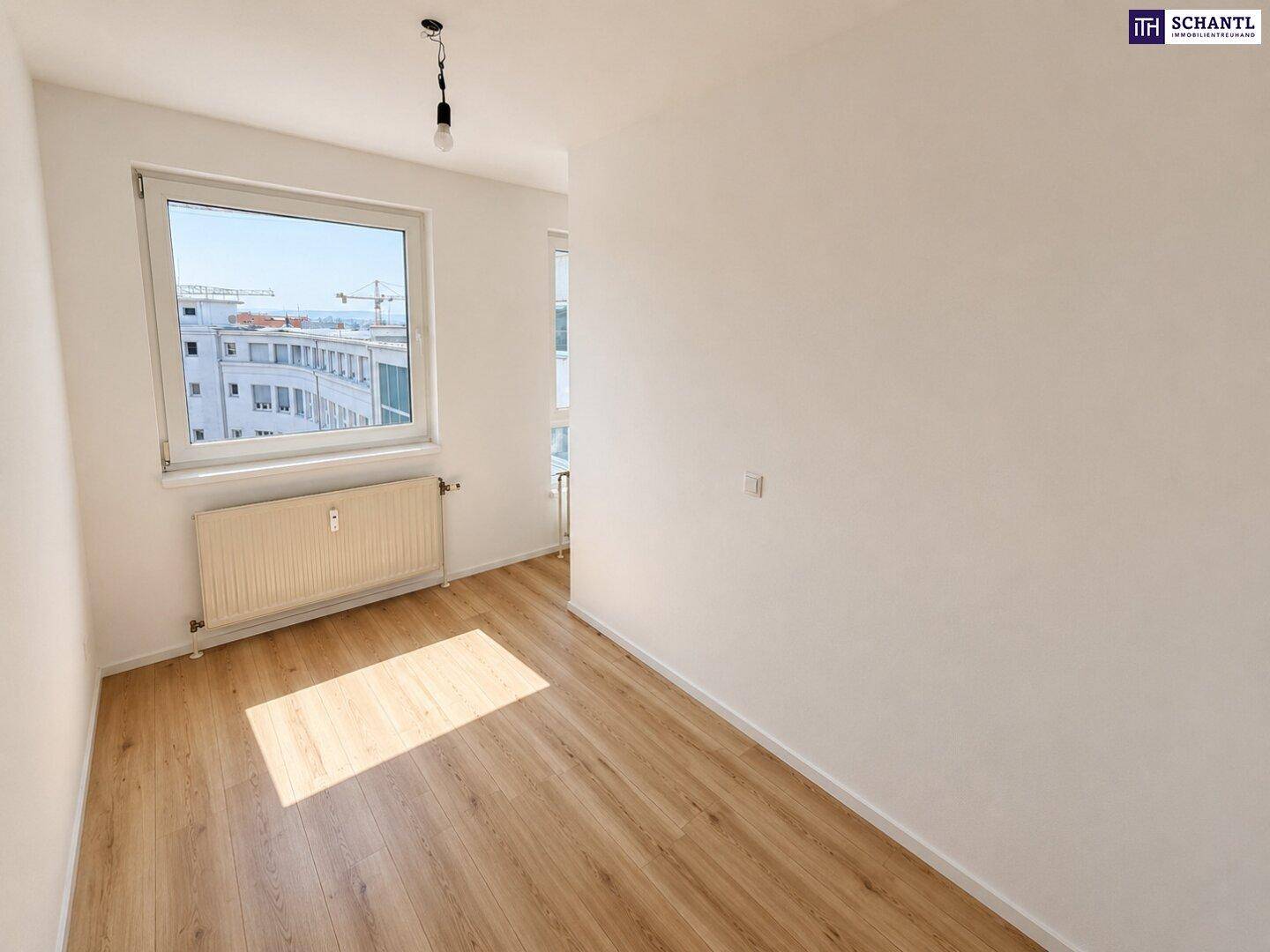 Helles Schlafzimmer mit Laminatboden, weißen Wänden und einem Fenster mit Blick auf die Stadt.