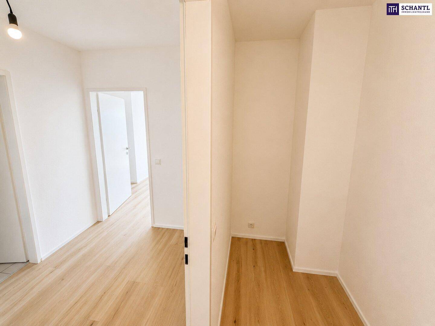 Heller Flur mit Laminatboden und weißen Wänden, der zu weiteren Räumen führt.