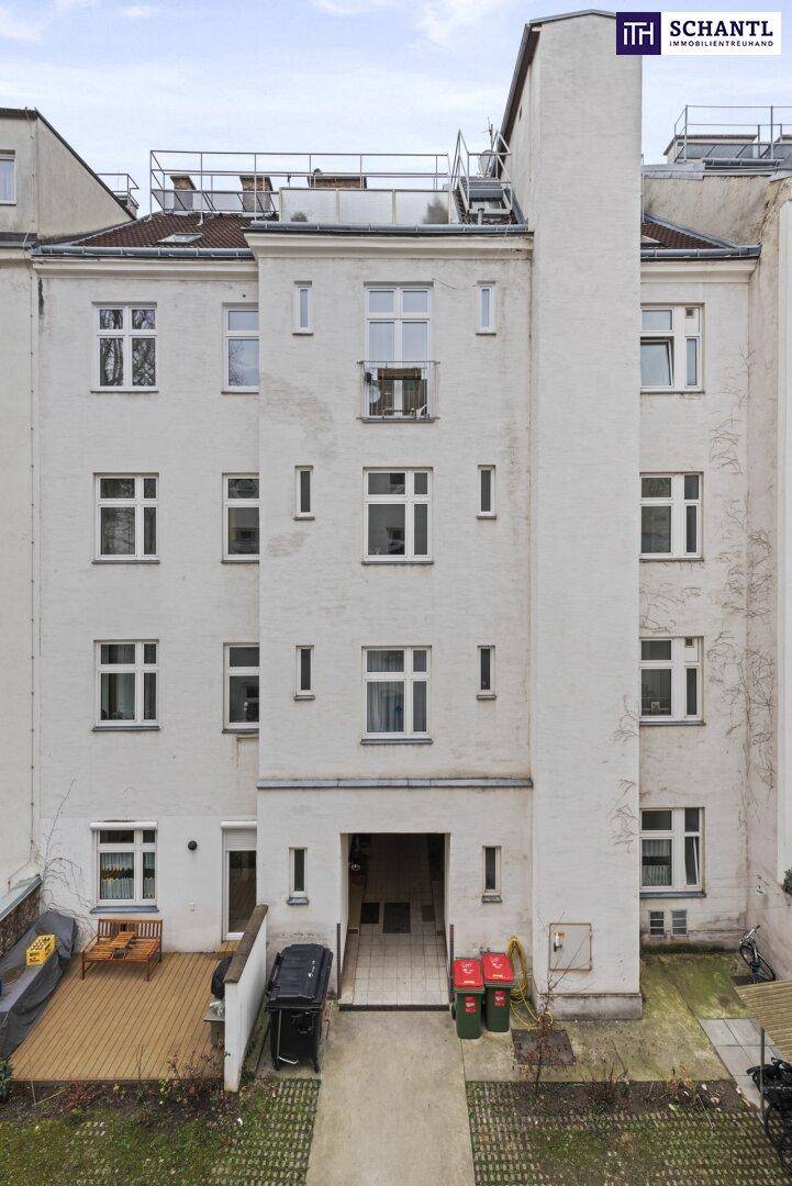 Rückfassade eines Mehrfamilienhauses mit vielen Fenstern und einem kleinen Balkon.