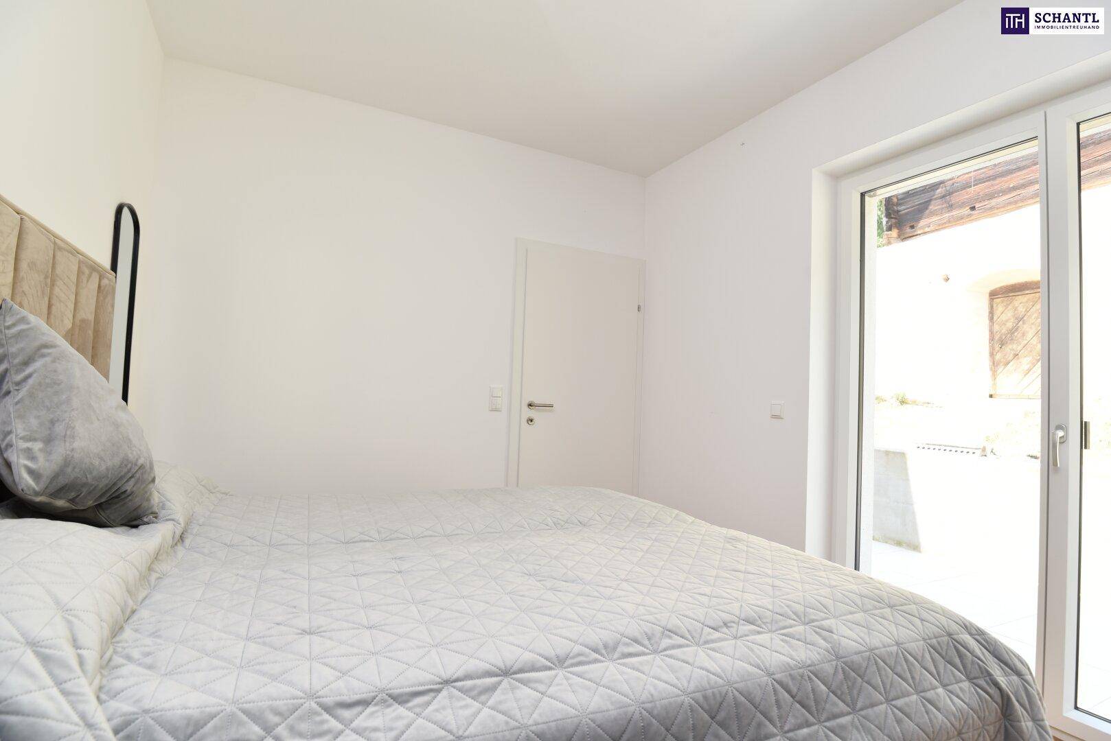 Helles Schlafzimmer mit Zugang zu einem Außenbereich und Holzboden.