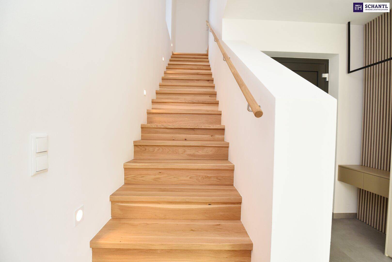 Helle Holztreppe mit weiß gestrichenen Wänden und einem schlichten Holzhandlauf.