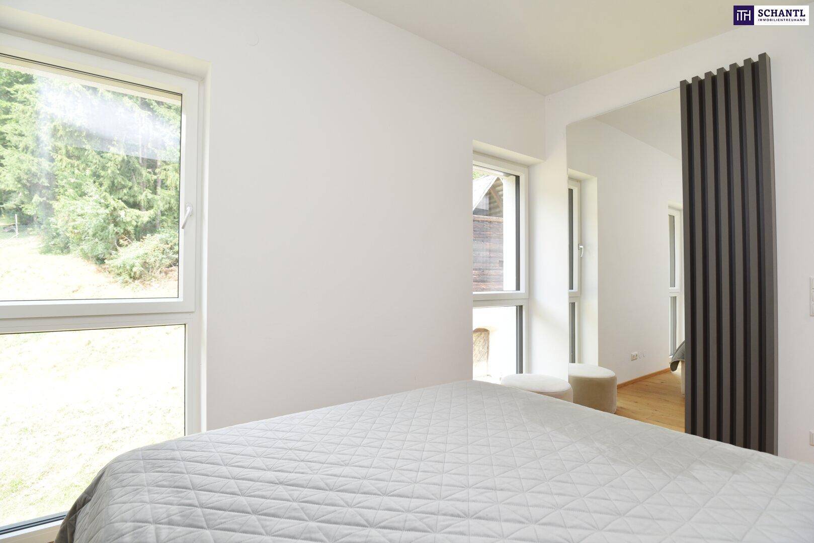 Schlafzimmer mit zwei großen Fenstern, die viel Licht und einen Blick ins Grüne ermöglichen.