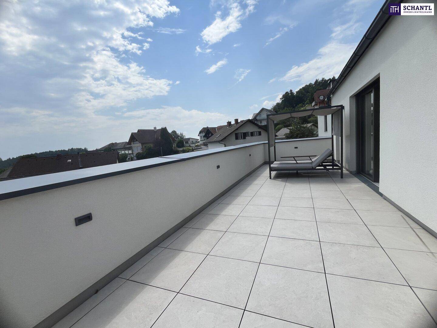 Große geflieste Terrasse mit Tagesliege und weitem Blick über die umliegende Wohngegend.