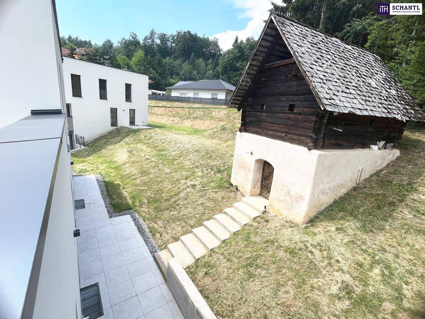 Blick von der Terrasse auf den Gartenbereich mit Steintreppe und einem charmanten Holzschuppen.