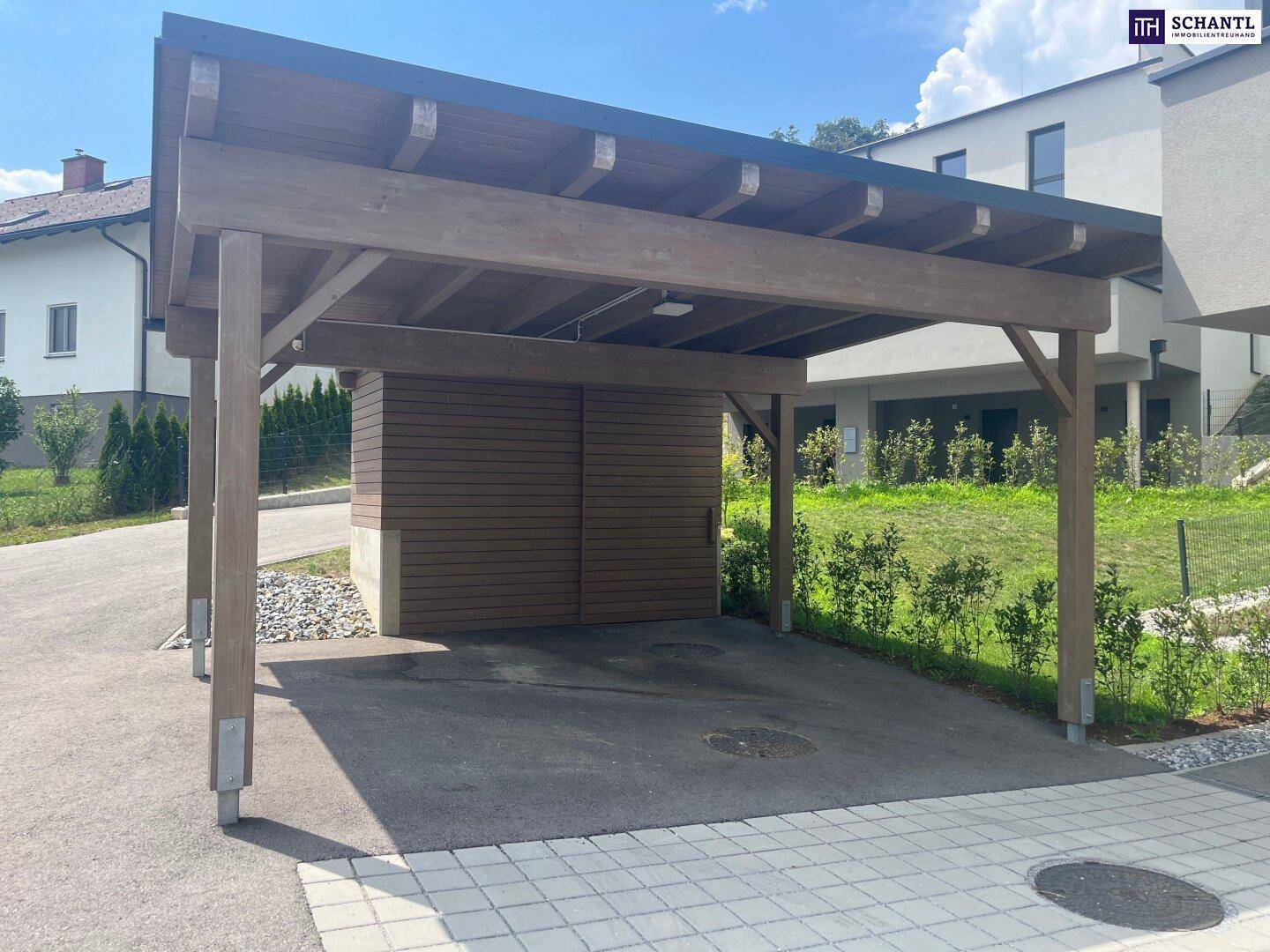 Moderner Holzcarport mit integriertem Abstellraum und gepflasterter Zufahrt.