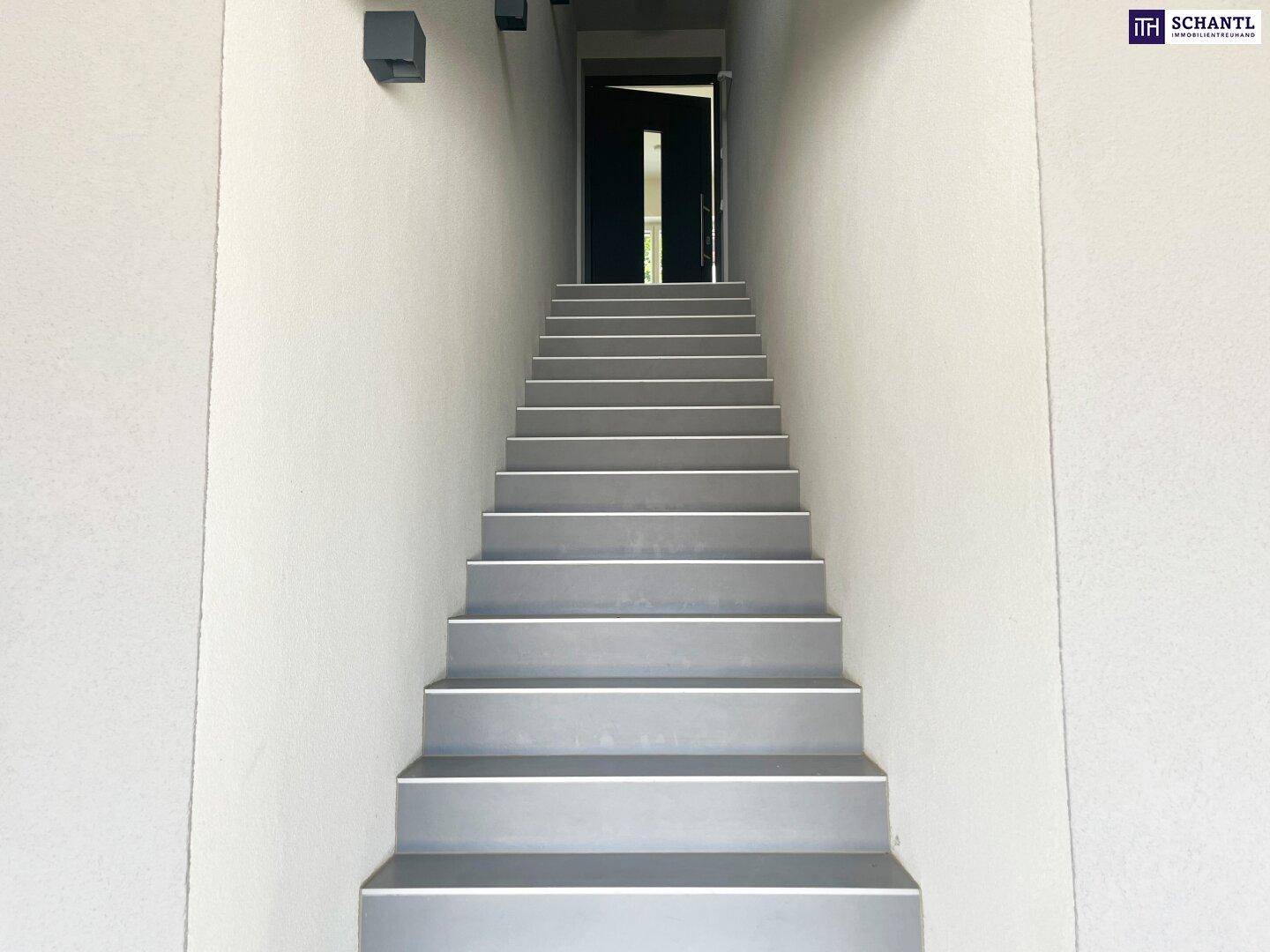 Heller Treppenaufgang mit grauen Stufen, der zum Eingangsbereich führt.