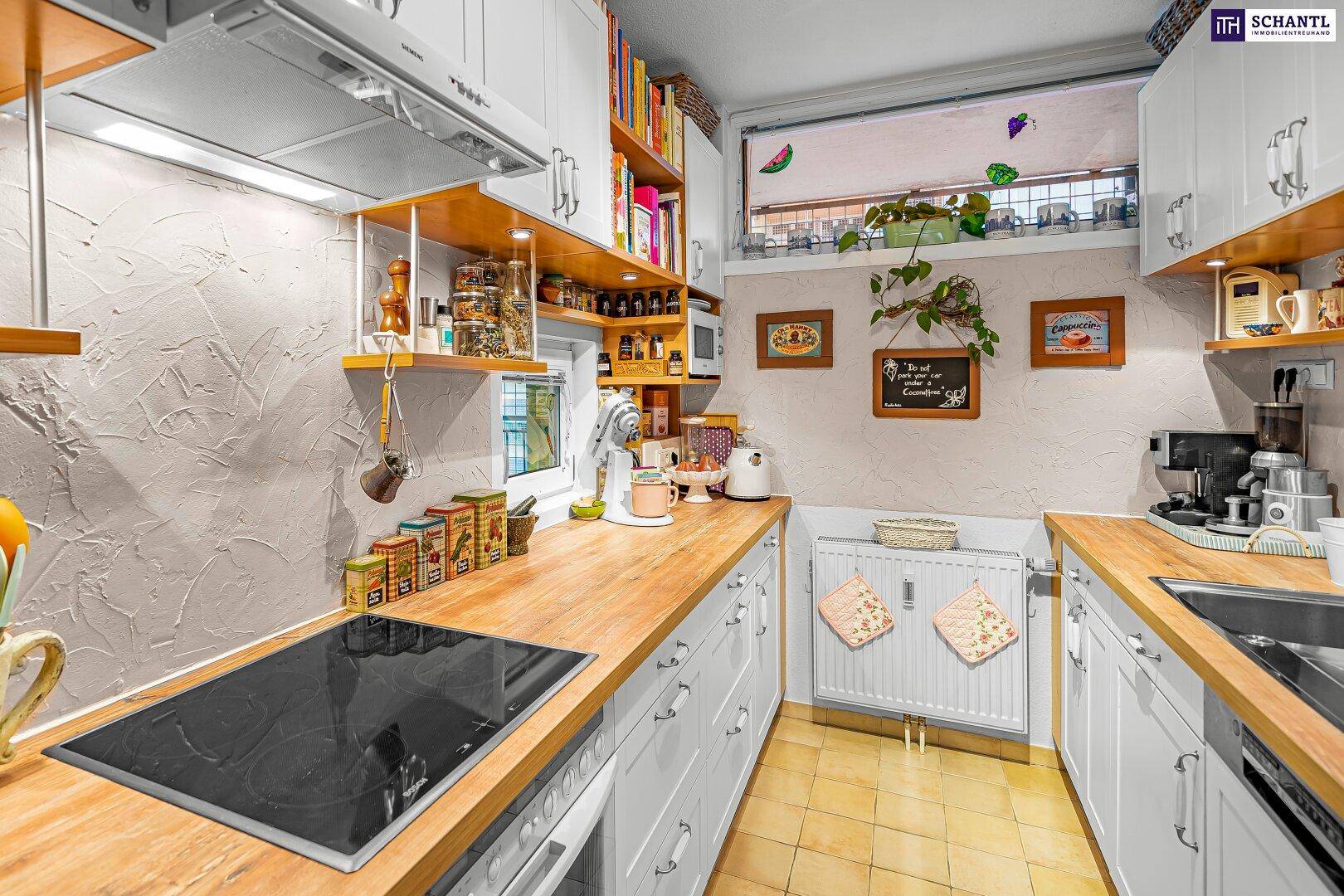 Funktionale Küche mit weißen Schränken, Holzarbeitsplatten und einem Fenster für Tageslicht.
