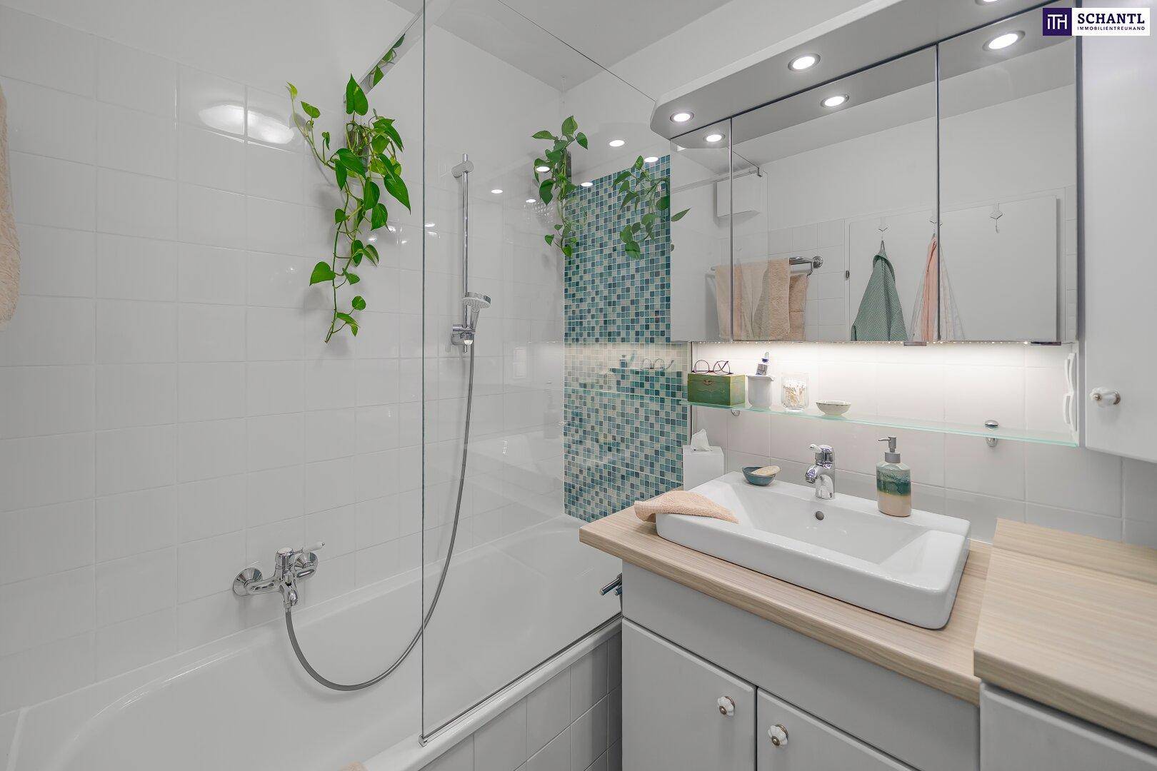 Modernes Badezimmer mit Badewanne, Duschwand und Einzelwaschbecken, hell gefliest.