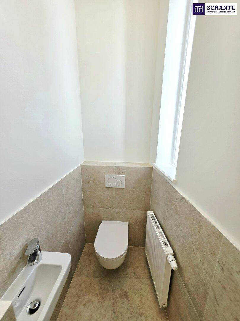 Modernes Gäste-WC mit Wand-WC, kleinem Waschbecken und Fenster für natürliche Belüftung.
