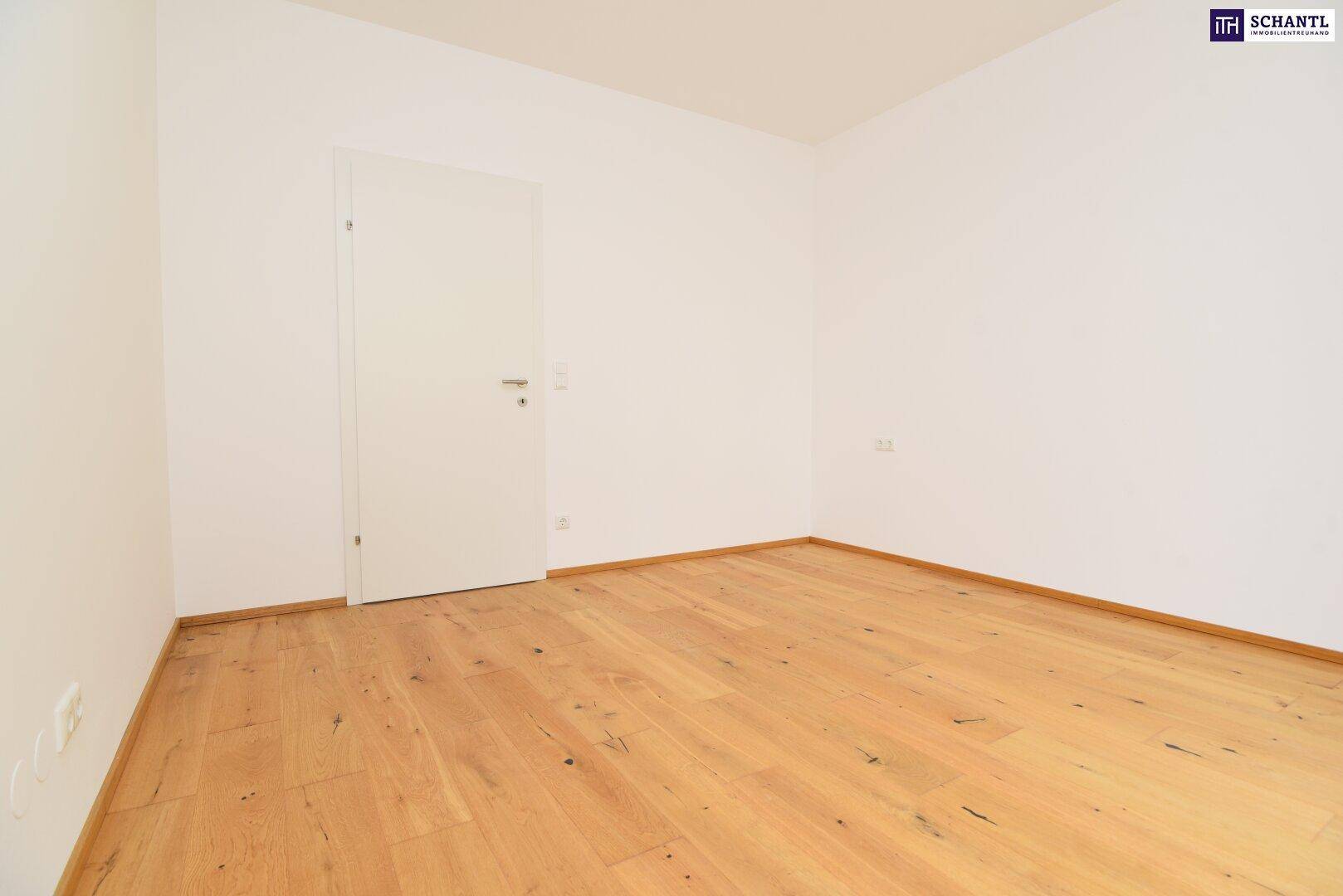 Helles Zimmer mit Holzboden und weißer Tür, bereit zur individuellen Gestaltung und Nutzung.