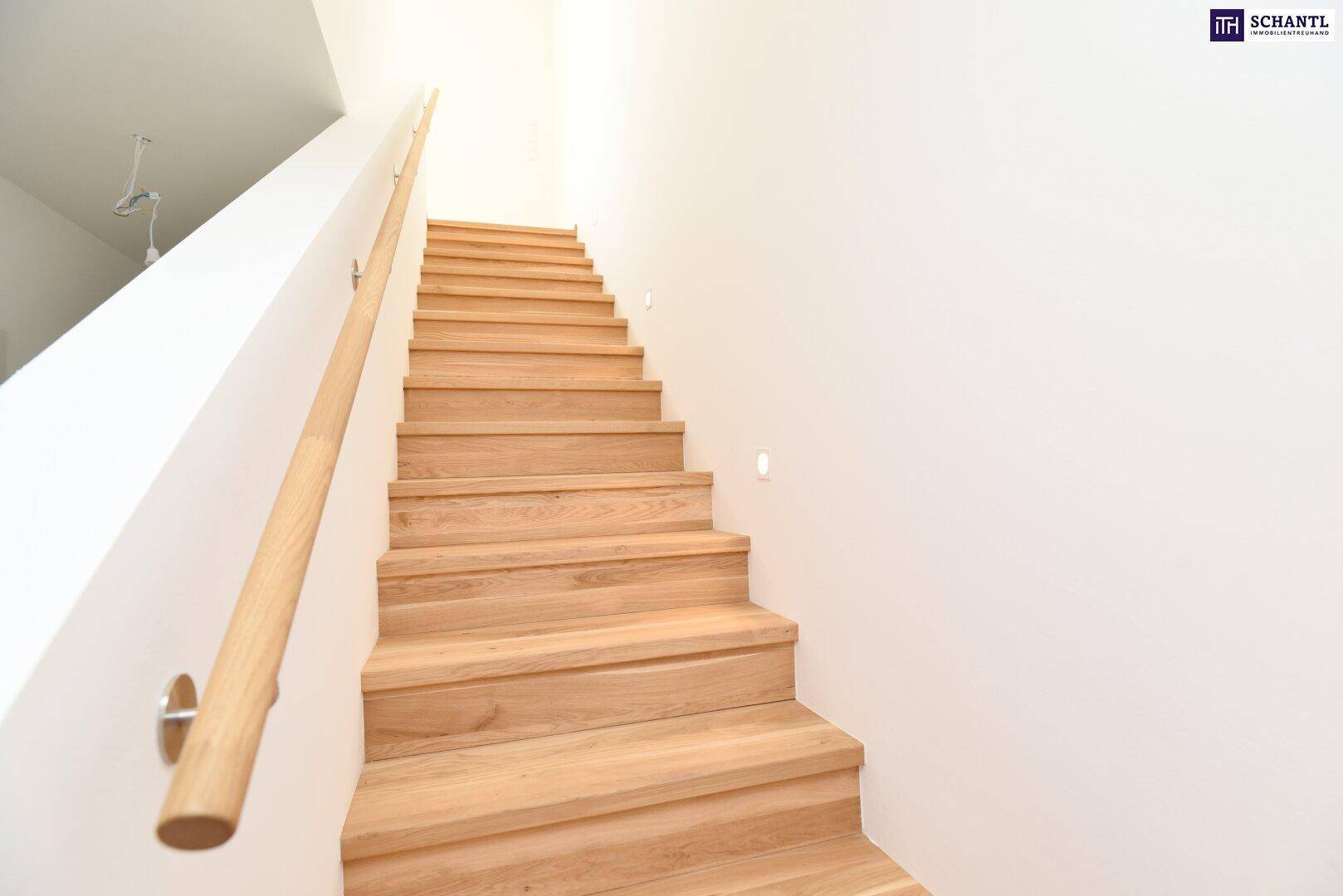 Helle Holztreppe mit modernem Geländer und integrierter Beleuchtung führt in die obere Etage.