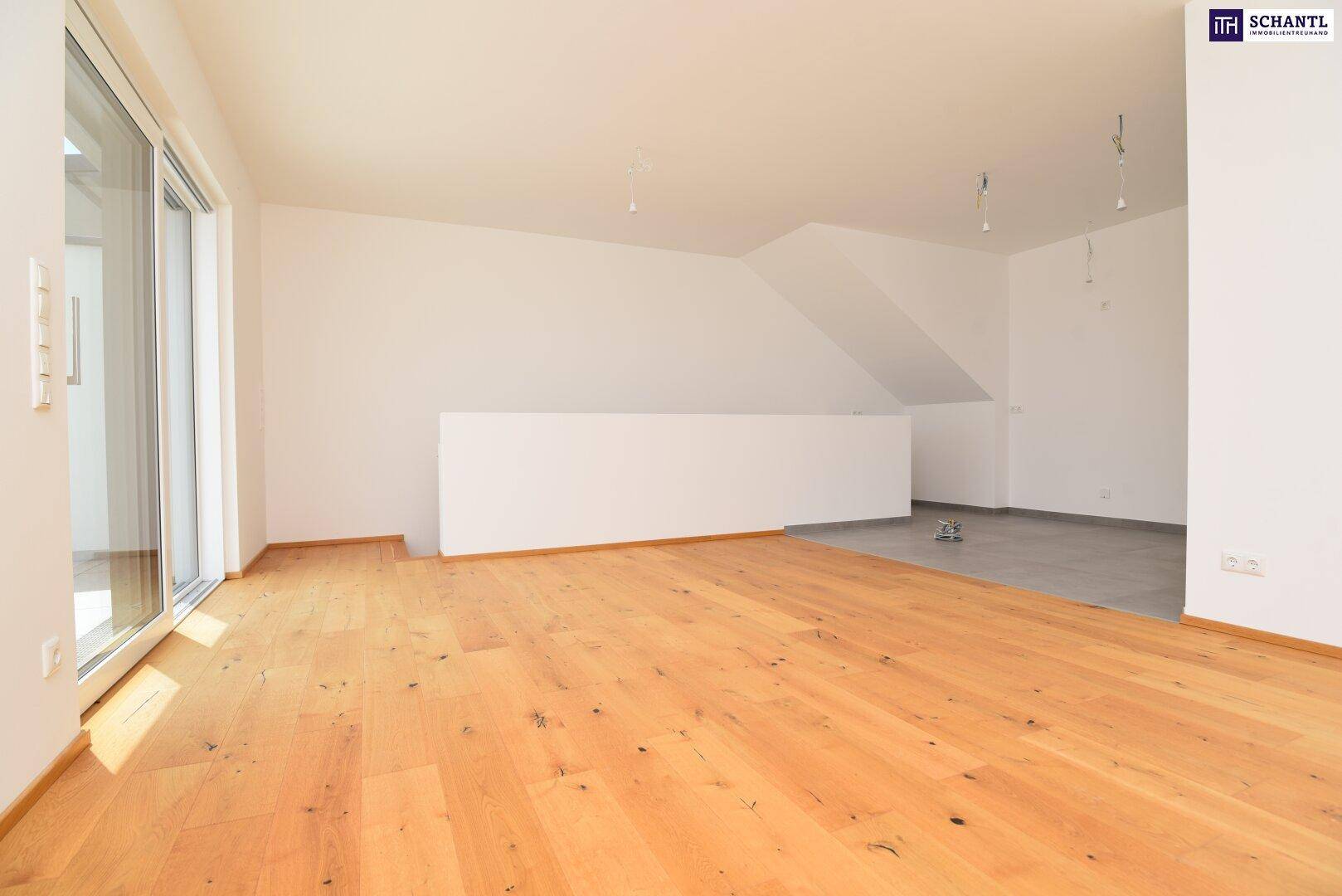 Heller Wohnbereich mit Holzboden, großen Fenstern und Zugang zu einer Außenterrasse.
