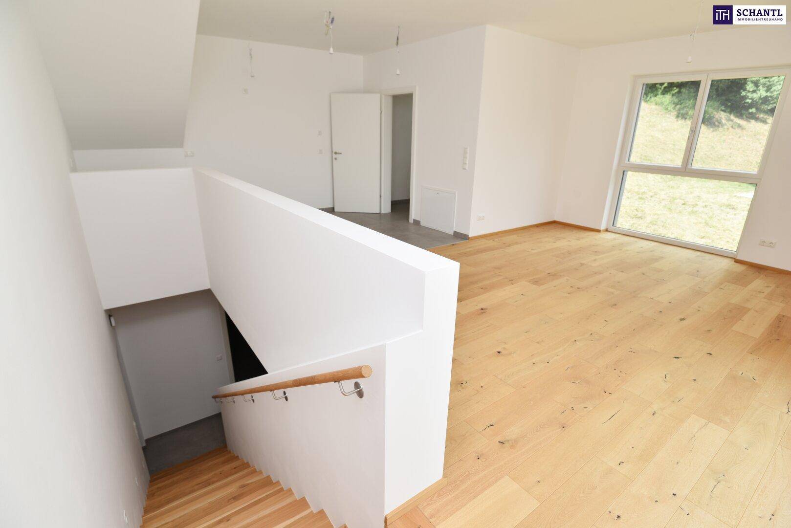 Heller Wohnbereich mit Holztreppe und großem Fenster, das viel Tageslicht hereinlässt.