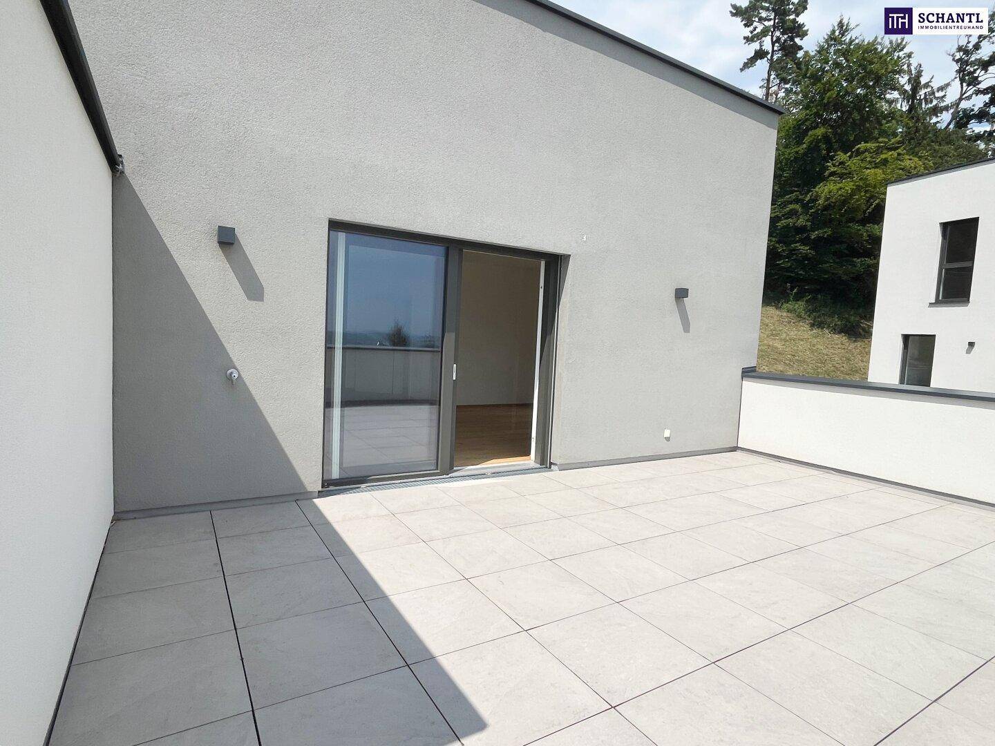 Moderne Terrasse mit Schiebetürzugang zu den Innenräumen und Blick auf die Umgebung.