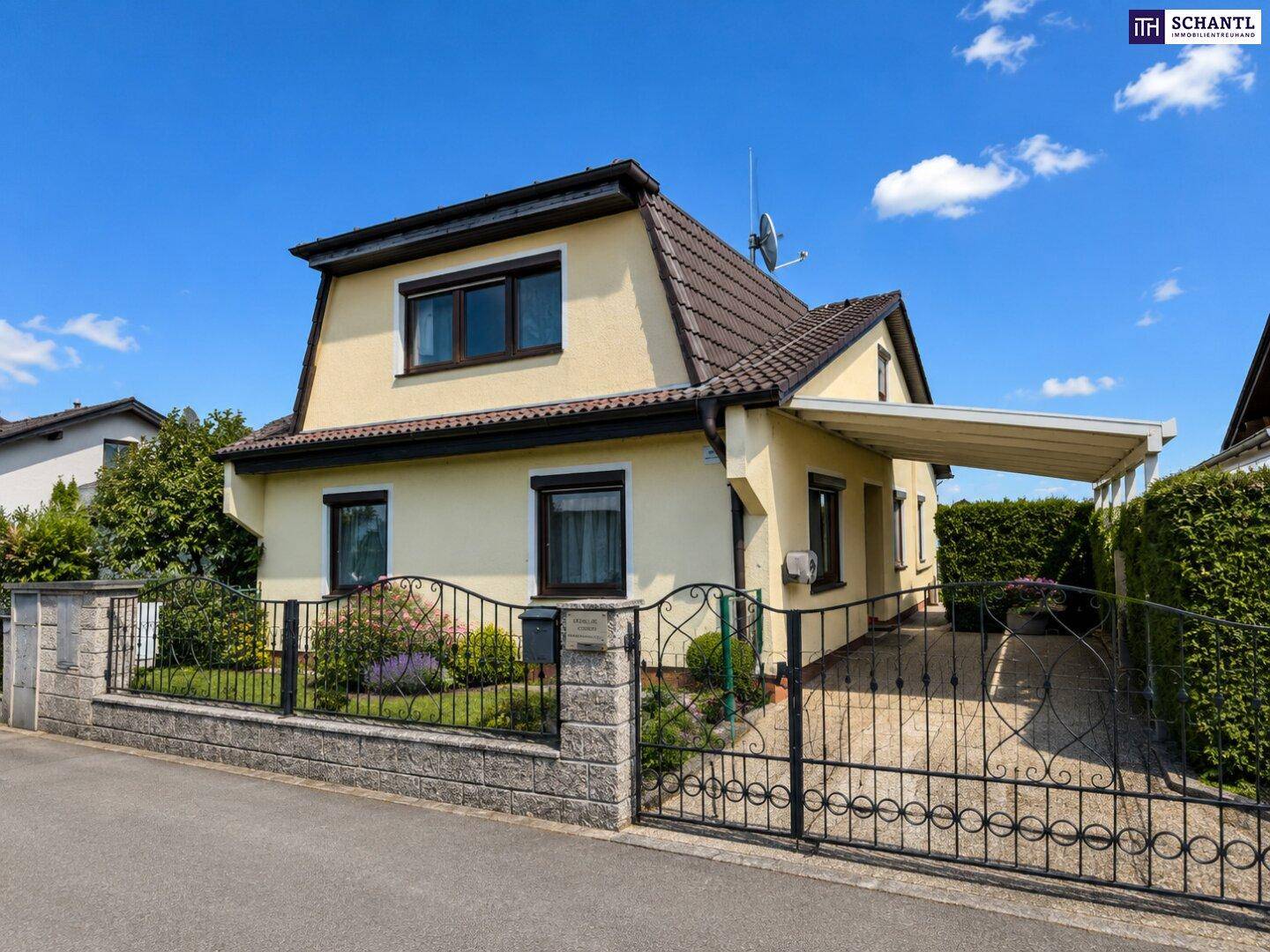Charmantes Einfamilienhaus mit Mansarddach, Vorgarten und schmiedeeisernem Zaun.