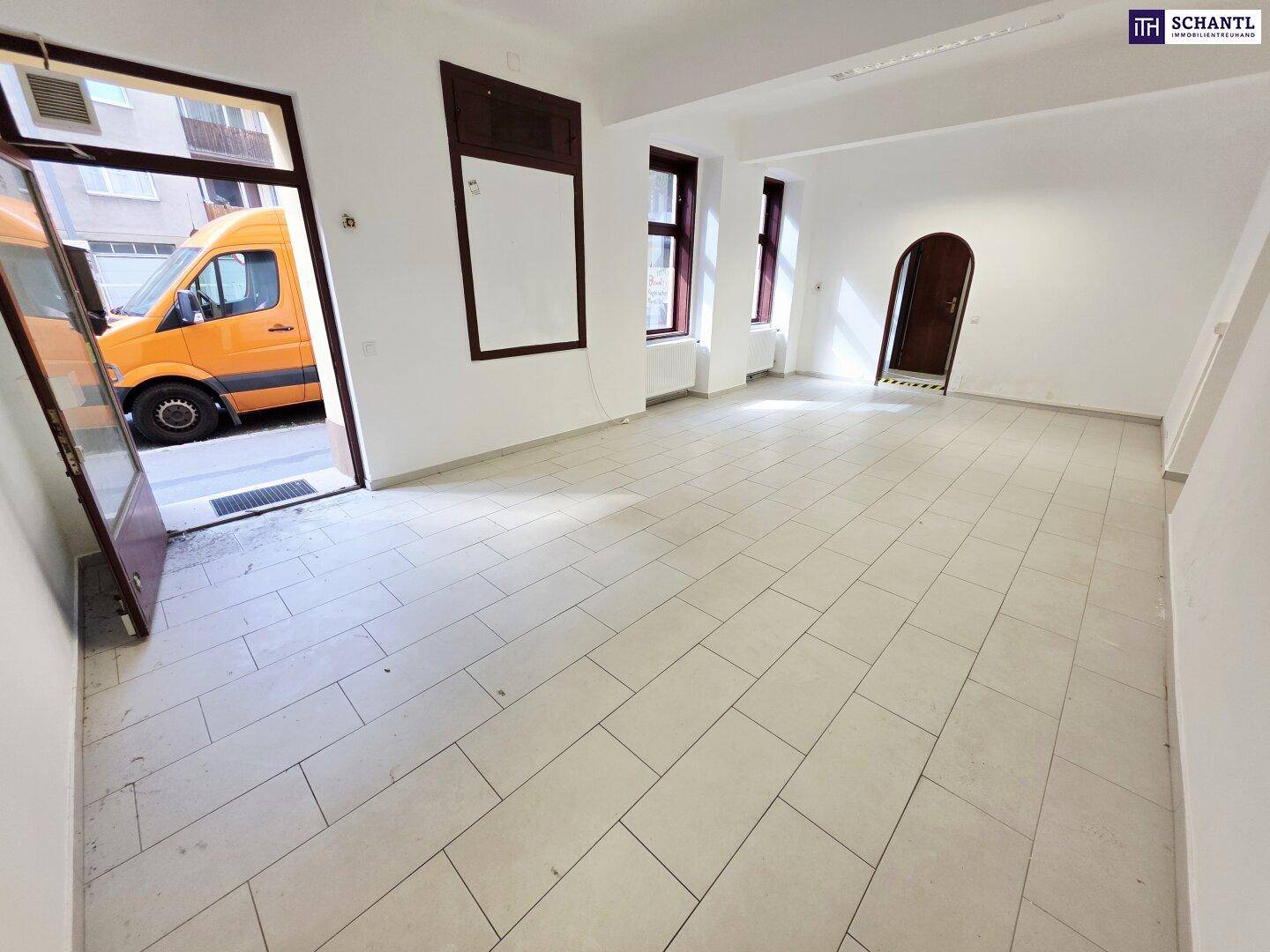 Heller Geschäftsraum mit Fliesenboden und offener Eingangstür zur Straße, die Tageslicht hereinlässt.