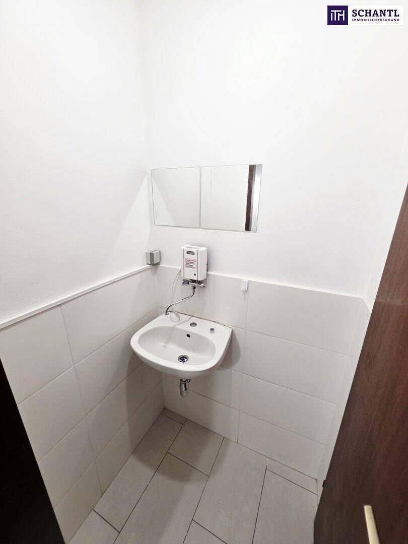 Kleines Badezimmer mit Waschbecken, Spiegel und weißen Fliesen an den Wänden.