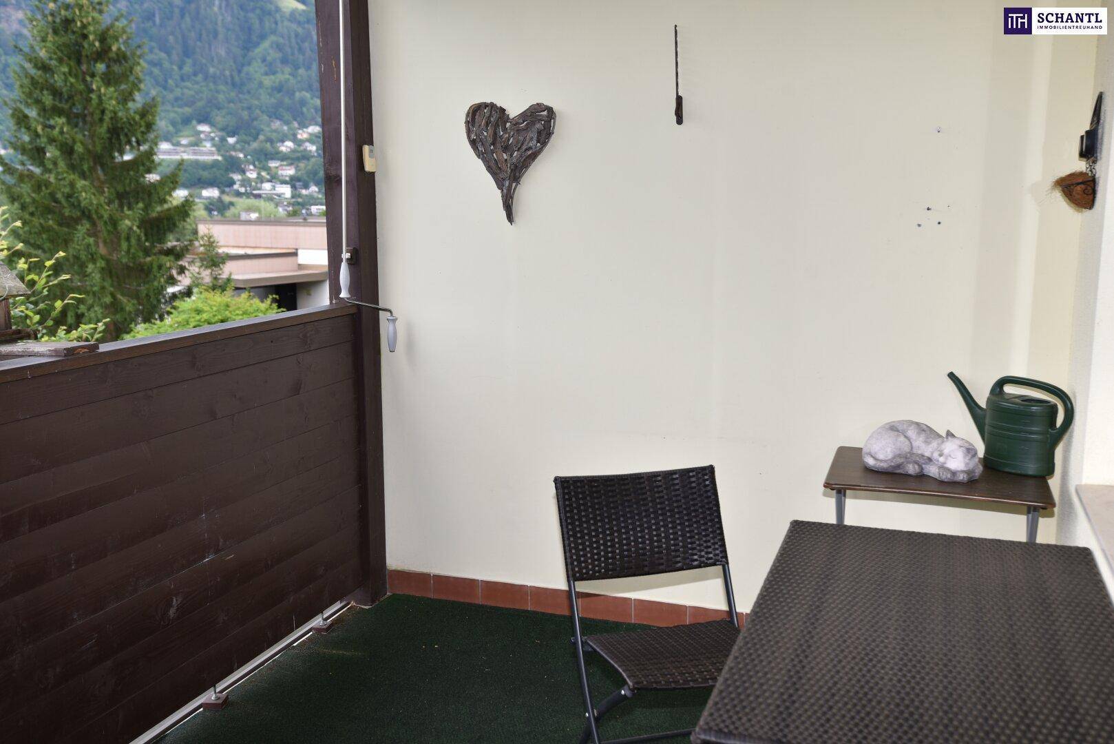 Kleiner Balkon mit Sitzgelegenheiten und Blick auf die grüne Umgebung und Berge.