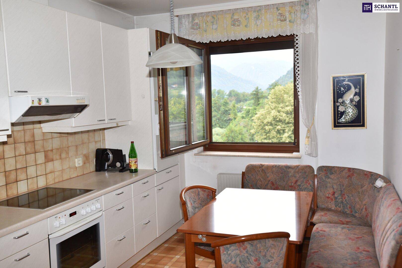 Funktionale Küche mit Essbereich, weißen Schränken und Fenster mit Blick auf die Berge.