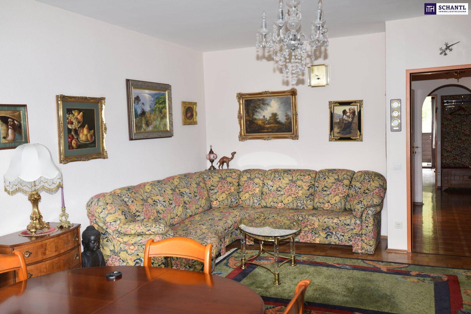 Geräumiges Wohnzimmer mit großem Ecksofa, traditionellen Gemälden und einem eleganten Kronleuchter.