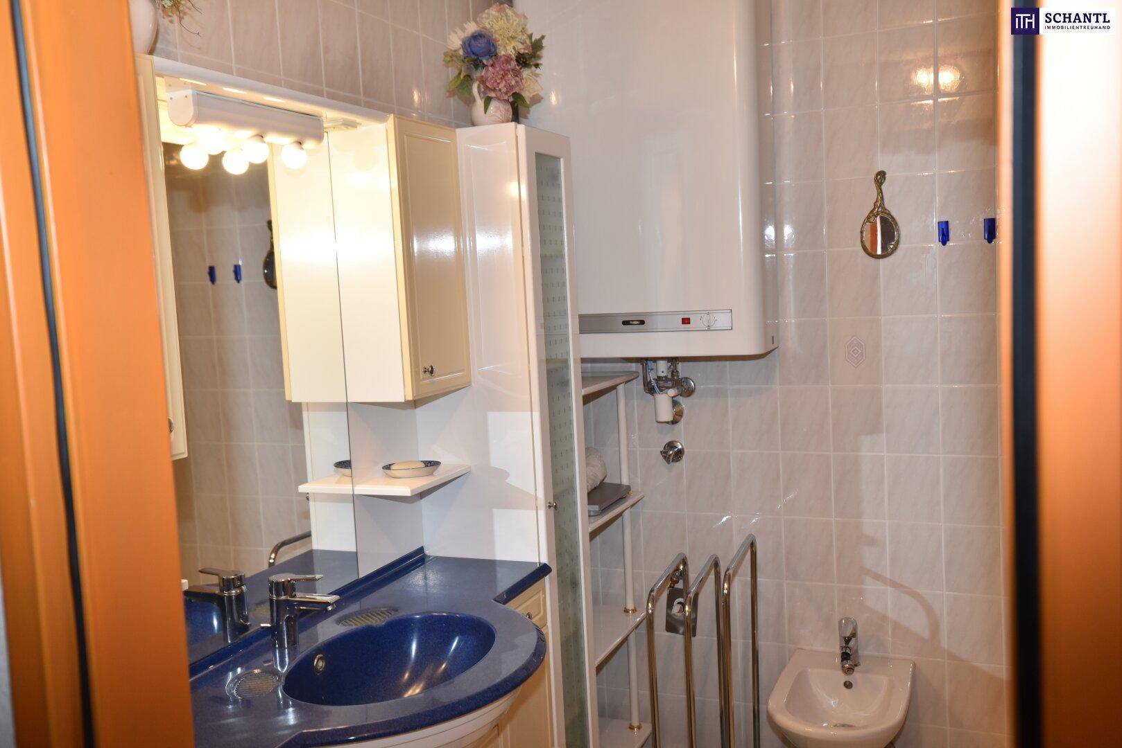 Badezimmer mit blauer Waschtischplatte, Spiegelschrank, Boiler und gefliesten Wänden.
