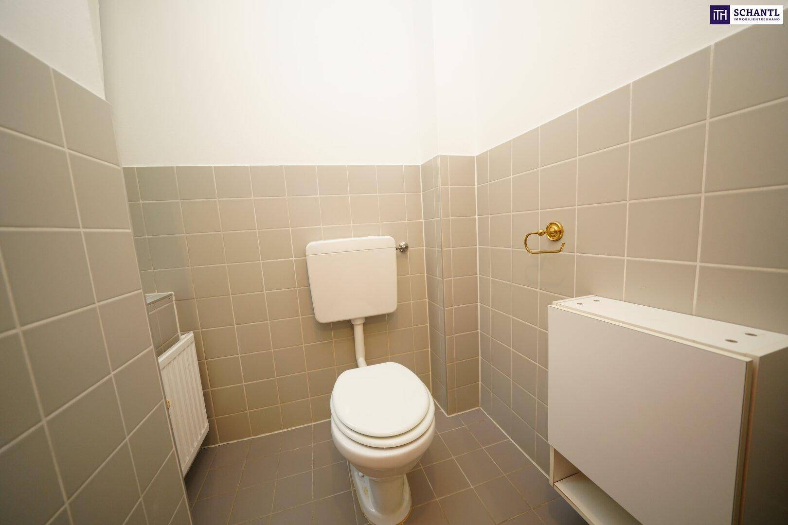 Separate Gästetoilette mit hellgrauen Fliesen an Wänden und Boden, die einen sauberen Eindruck macht.