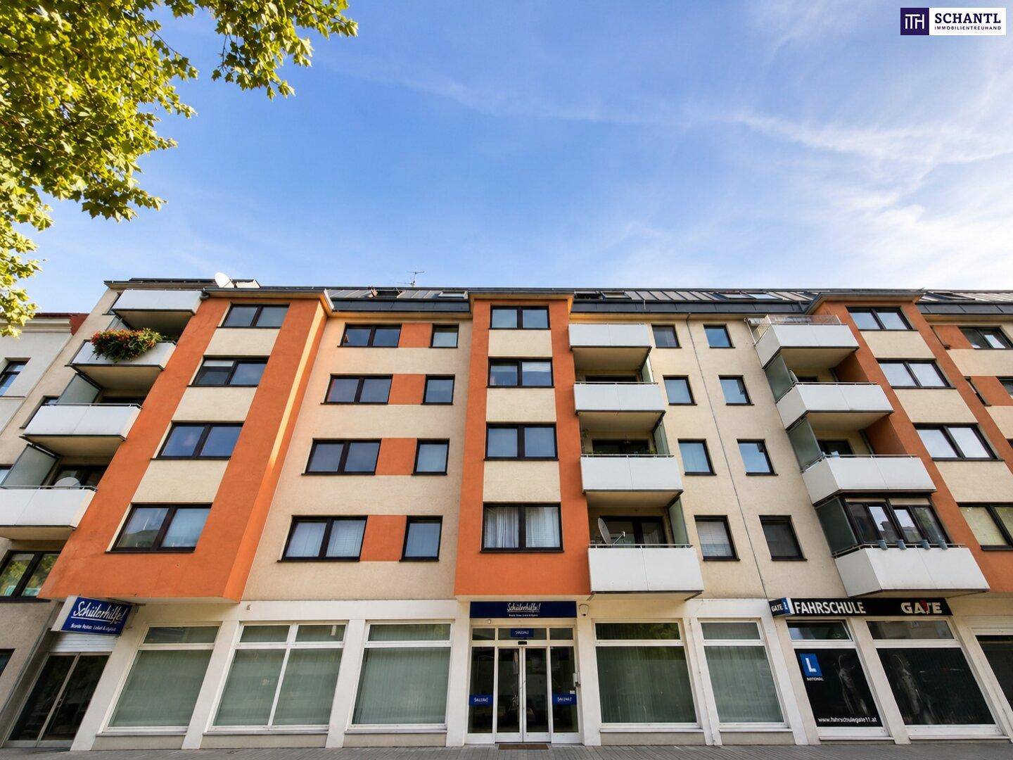 Mehrfamilienhaus mit orangefarbenen Akzenten, Balkonen und Geschäften im Erdgeschoss.