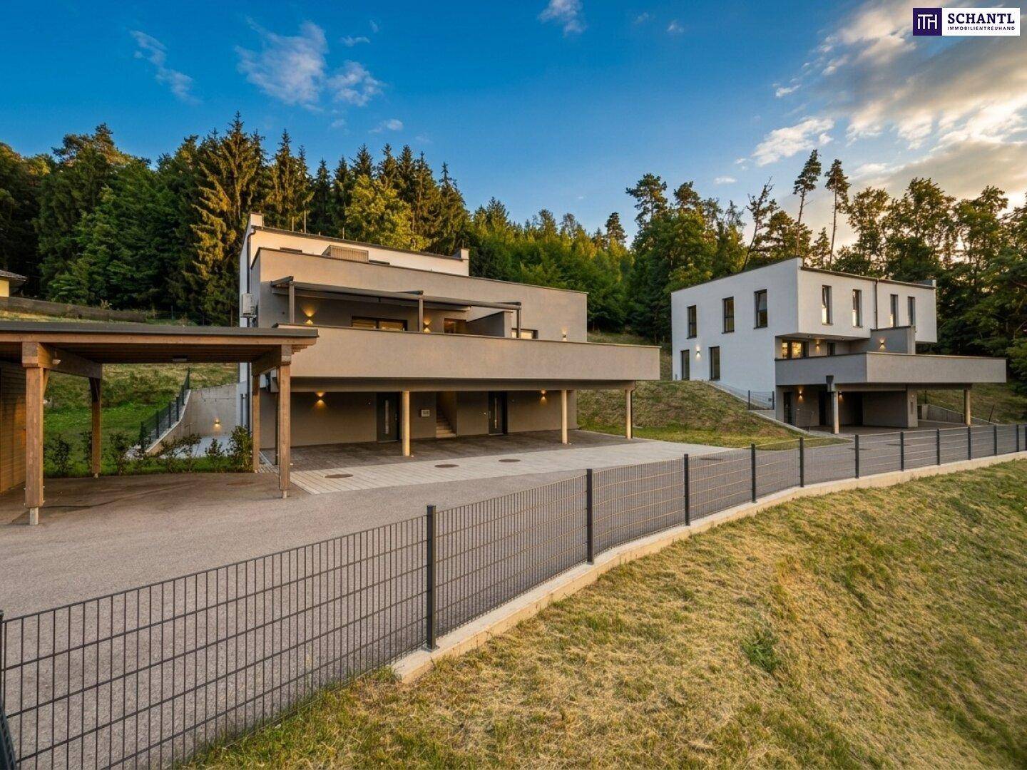 Zwei moderne Wohnhäuser in Hanglage mit großzügigen Balkonen und grüner Umgebung.