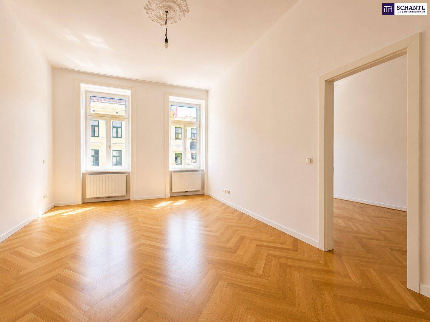 Geräumiges Zimmer mit Fischgrätparkett, dekorativer Stuckrosette an der Decke und viel Tageslicht.