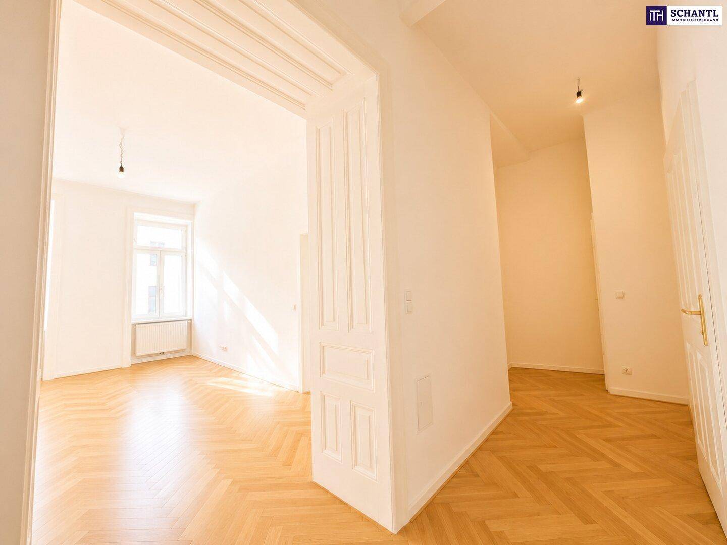 Geräumiger Flur mit Fischgrätparkett, der in ein helles Zimmer mit hohen Decken und Fenster führt.