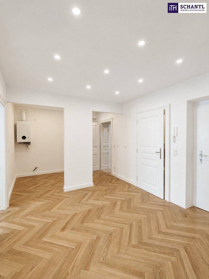 Heller Flur mit Fischgrätparkett, mehreren Türen und einer Gastherme an der Wand.