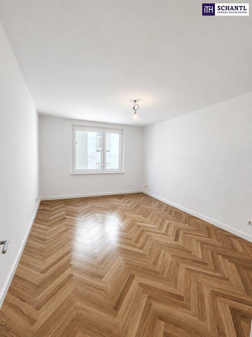 Geräumiger, heller Raum mit elegantem Fischgrätparkett und einem großen Fenster.