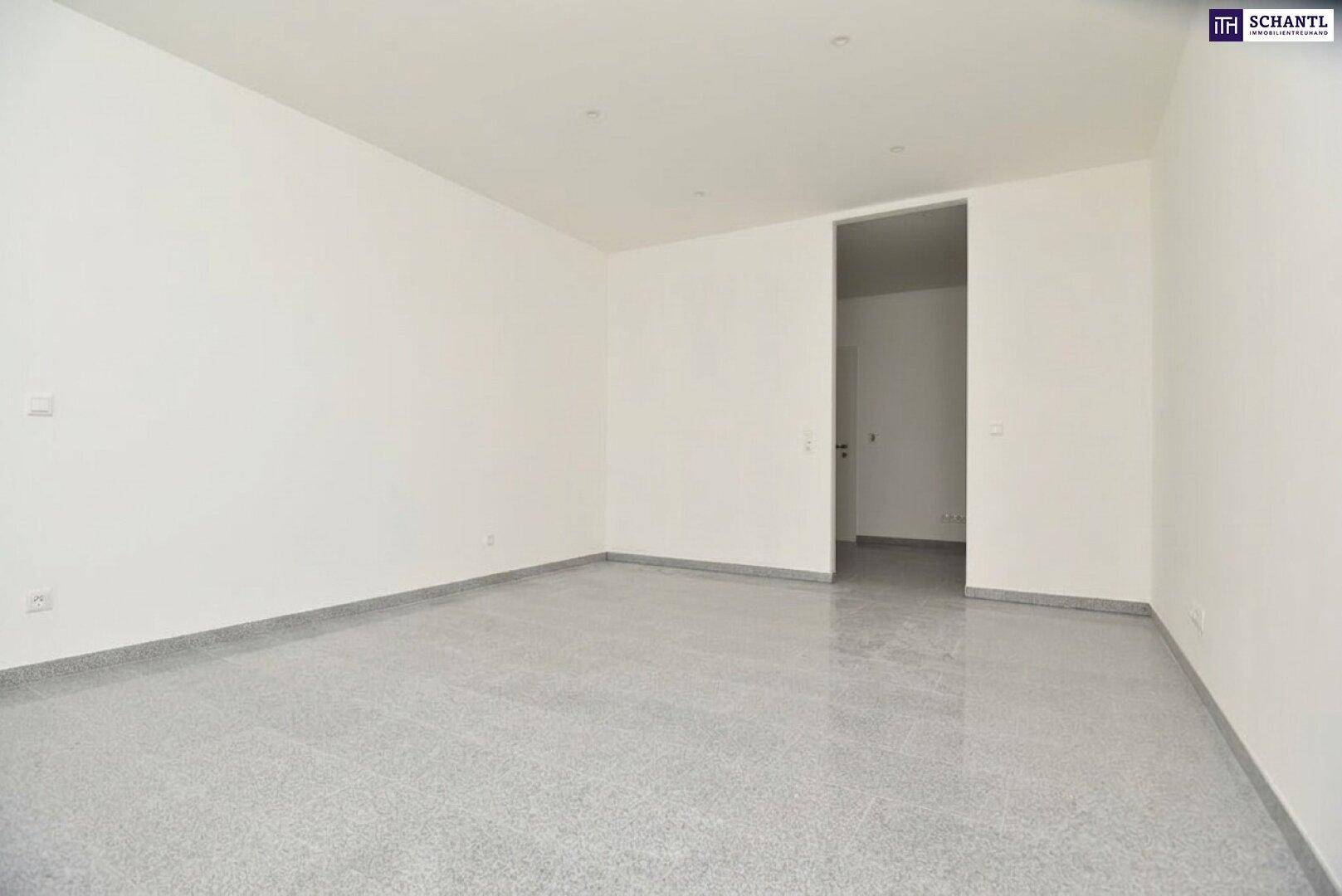 Geräumiger, leerer Raum mit grauen Fliesen und weißen Wänden, bereit zur individuellen Einrichtung.