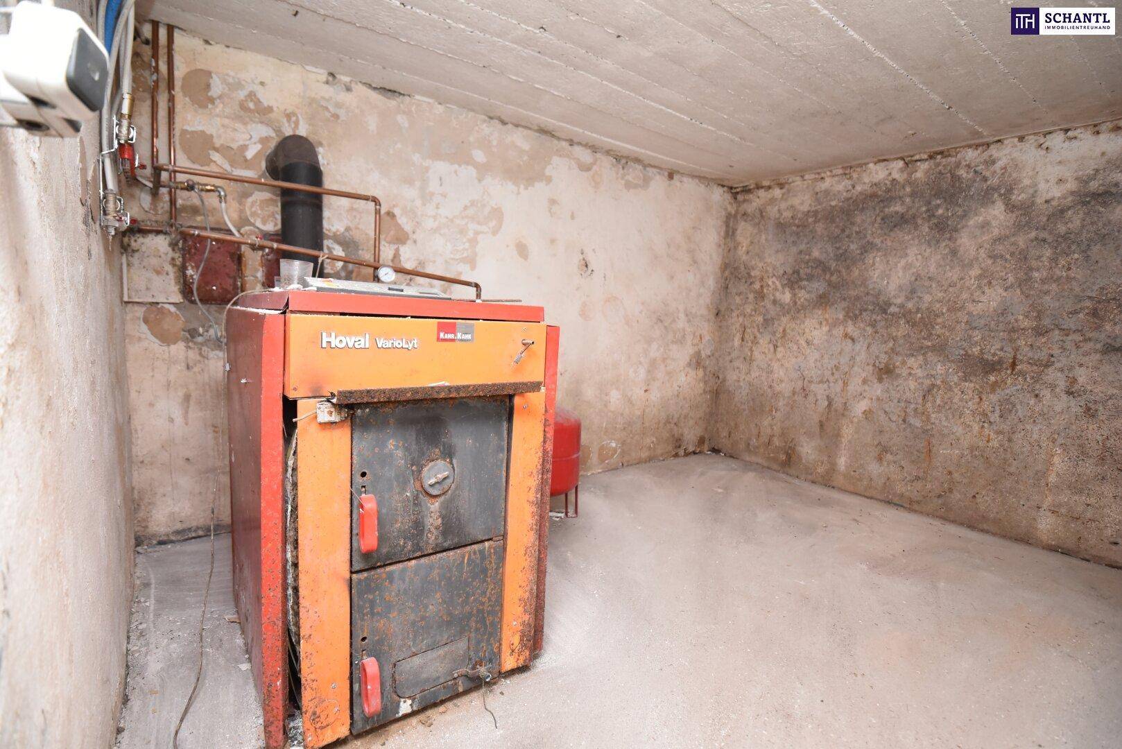 Heizraum im Keller mit einem alten Hoval-Heizkessel und abgenutzten Wänden.