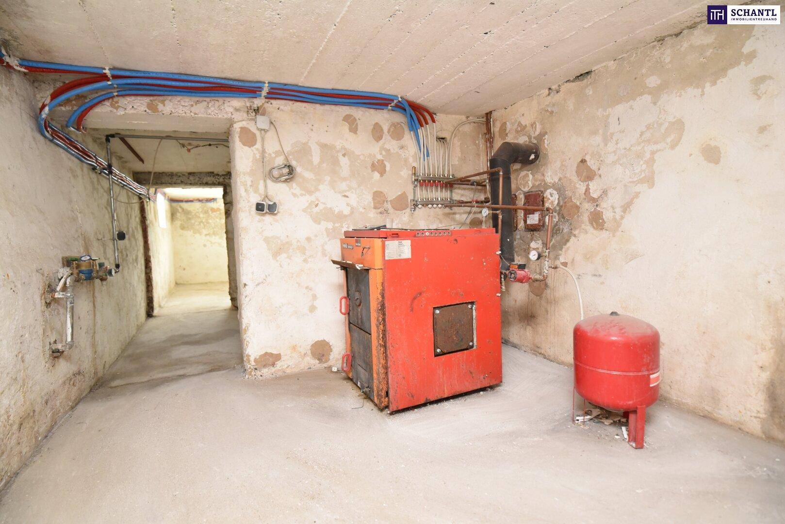 Kellerraum mit Heizkessel und sichtbaren Rohrleitungen, der als Technikraum dient.