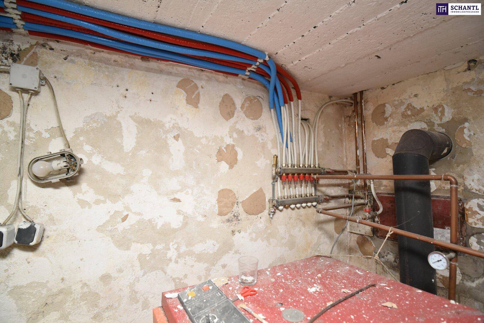 Detailansicht der Heizungsrohre und des Verteilers im Keller, die eine Modernisierung erfordern.