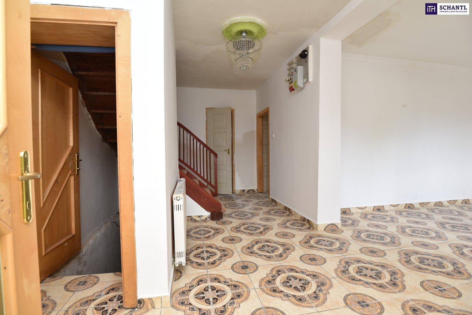 Eingangsbereich mit gemusterten Fliesen, Treppe zum Obergeschoss und Holztüren.