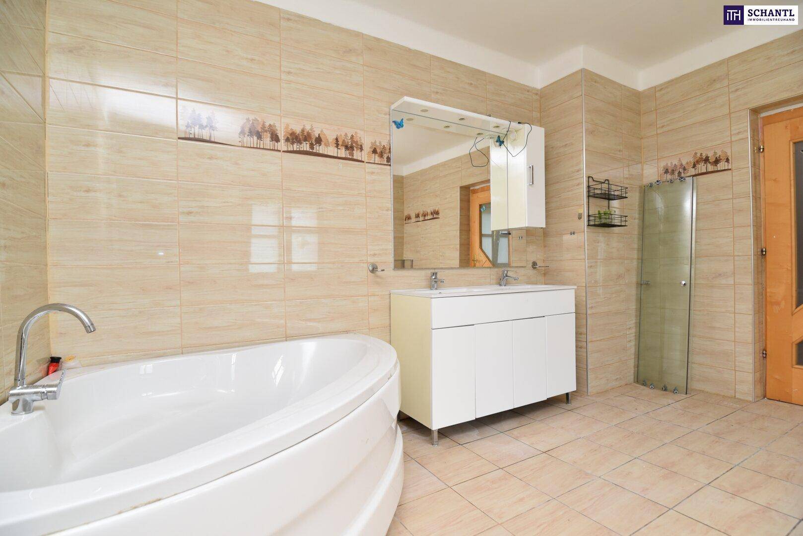 Helles Badezimmer mit beigefarbenen Fliesen, Doppelwaschbecken und großem Spiegel, mit Badewanne.