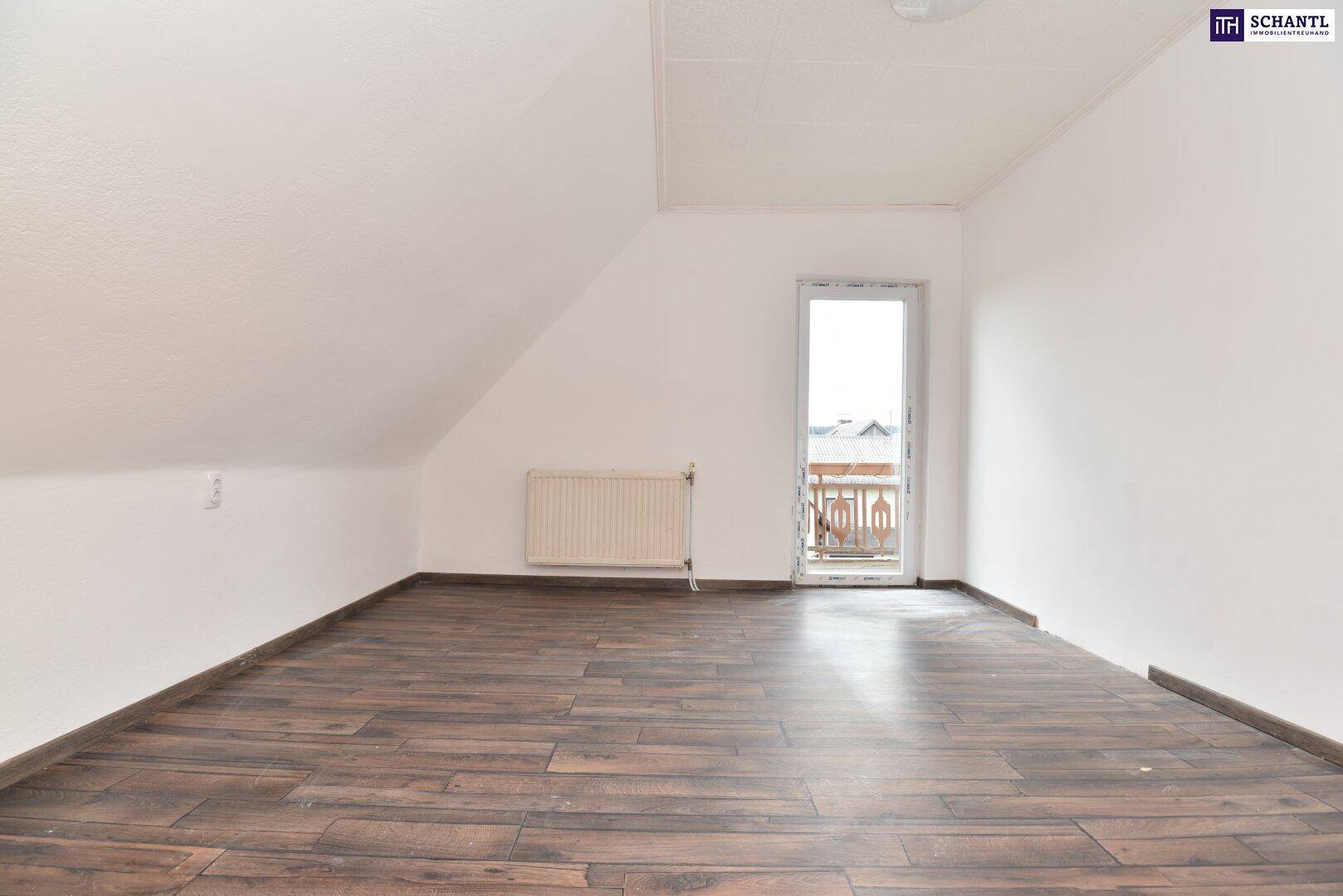 Dachgeschosszimmer mit dunklem Holzboden, weißen Wänden und direktem Zugang zu einem Balkon.