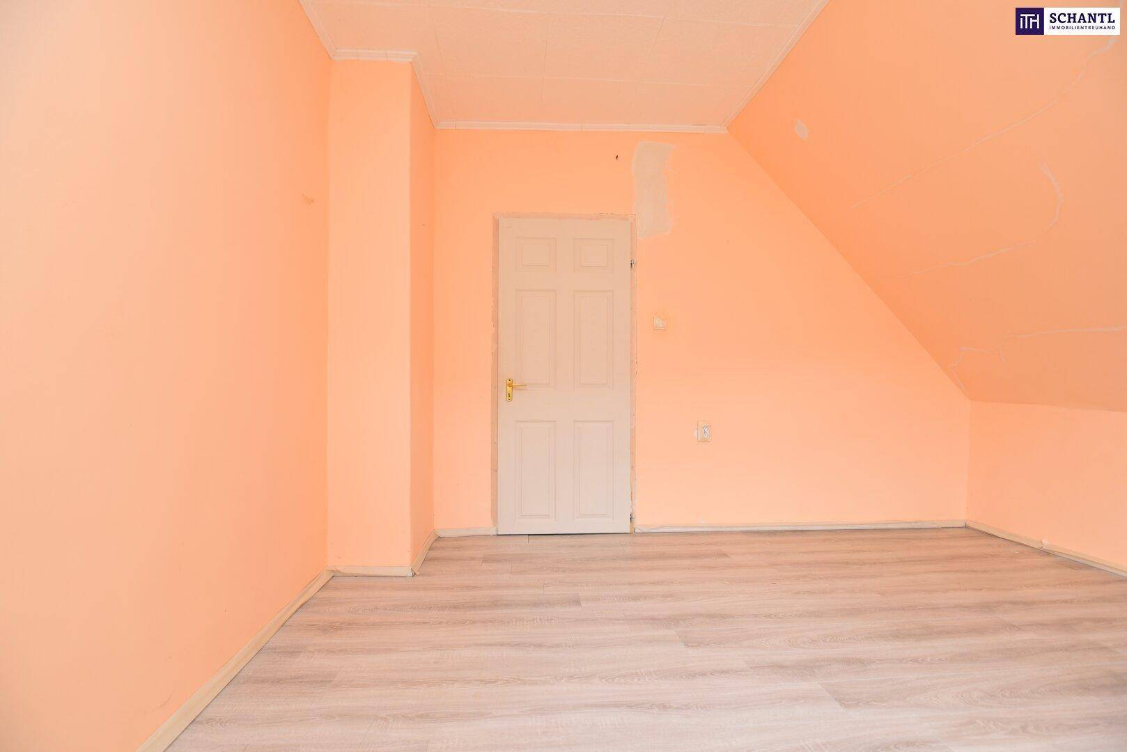 Dachgeschosszimmer mit hellem Laminatboden, pfirsichfarbenen Wänden und einer einfachen Holztür.