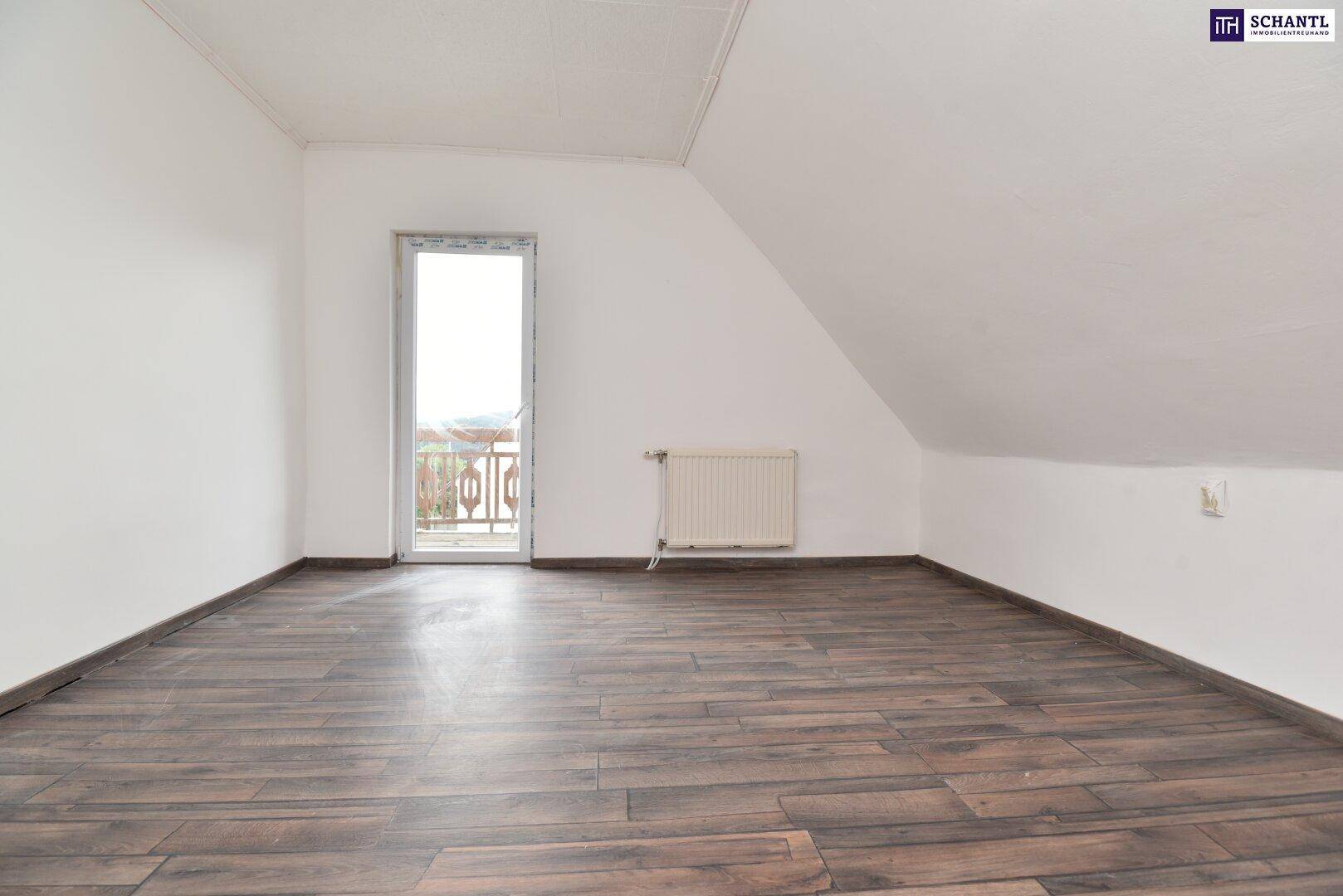 Dachgeschosszimmer mit dunklem Holzboden, weißen Wänden und Zugang zu einem Außenbalkon.
