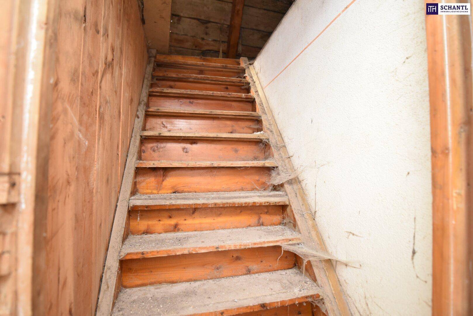 Alte Holztreppe, die zum Dachboden führt, mit sichtbaren Holzstufen und Spuren der Zeit.