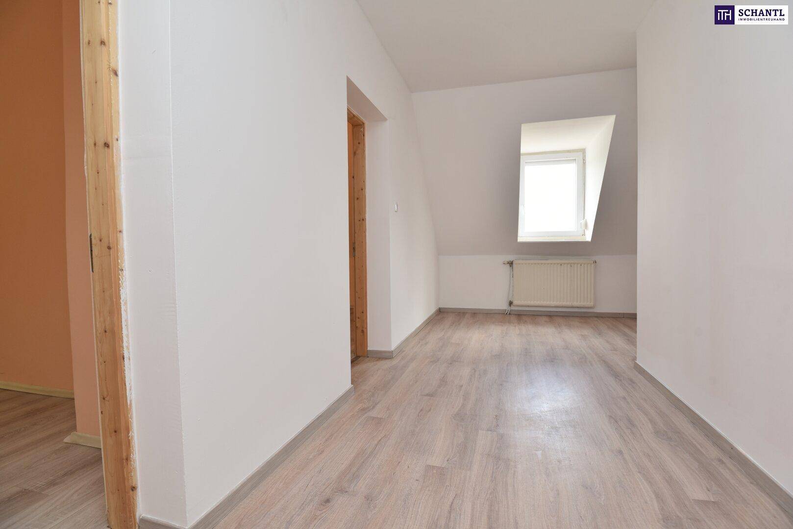 Leerer Raum im Dachgeschoss mit hellem Laminatboden, weißen Wänden, schräger Decke und einem Fenster.