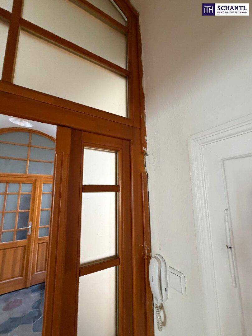 Eingangsbereich mit Holztürrahmen und Gegensprechanlage, der den Zugang zur Wohnung markiert.