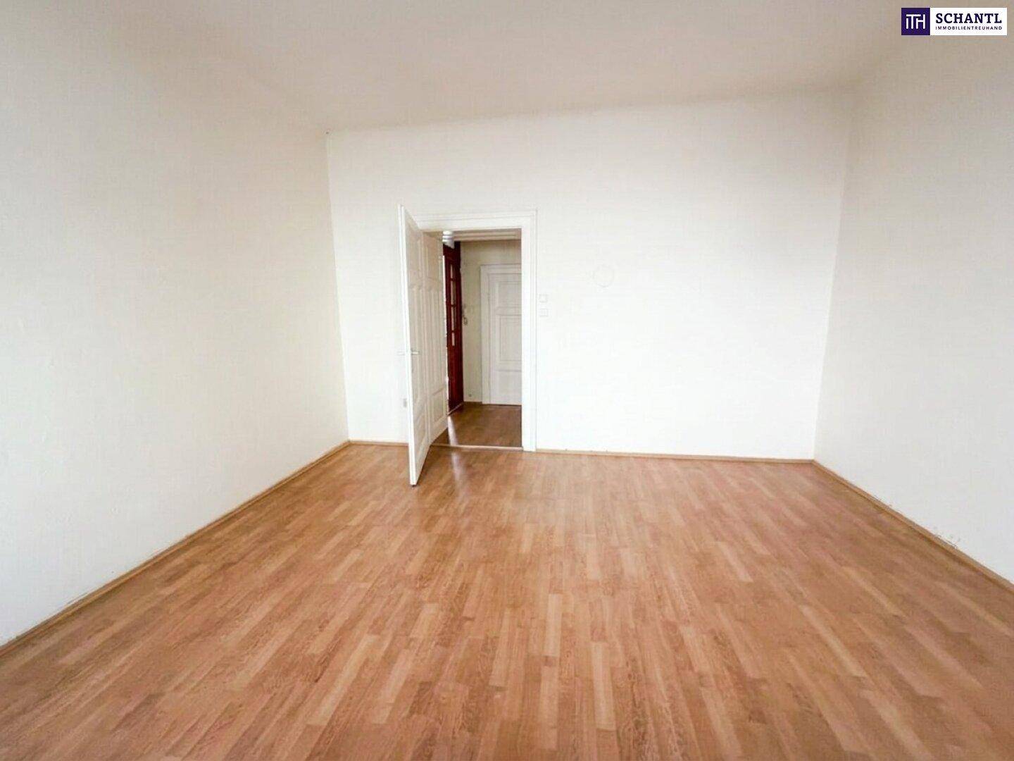 Geräumiges, leeres Zimmer mit Laminatboden und offener Tür zu einem weiteren Bereich.