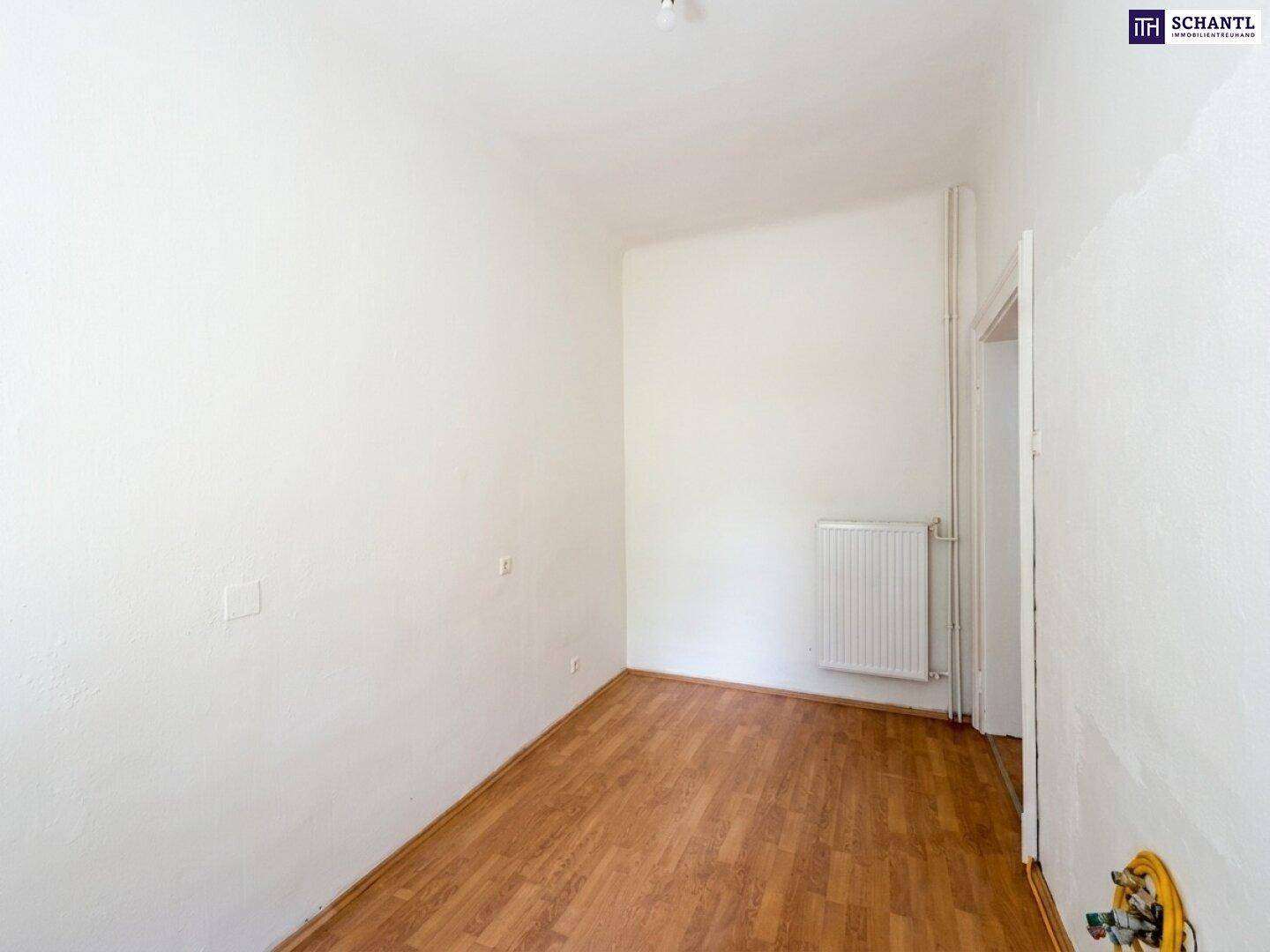 Leeres Zimmer mit Laminatboden und Heizkörper, bereit für neue Bewohner.