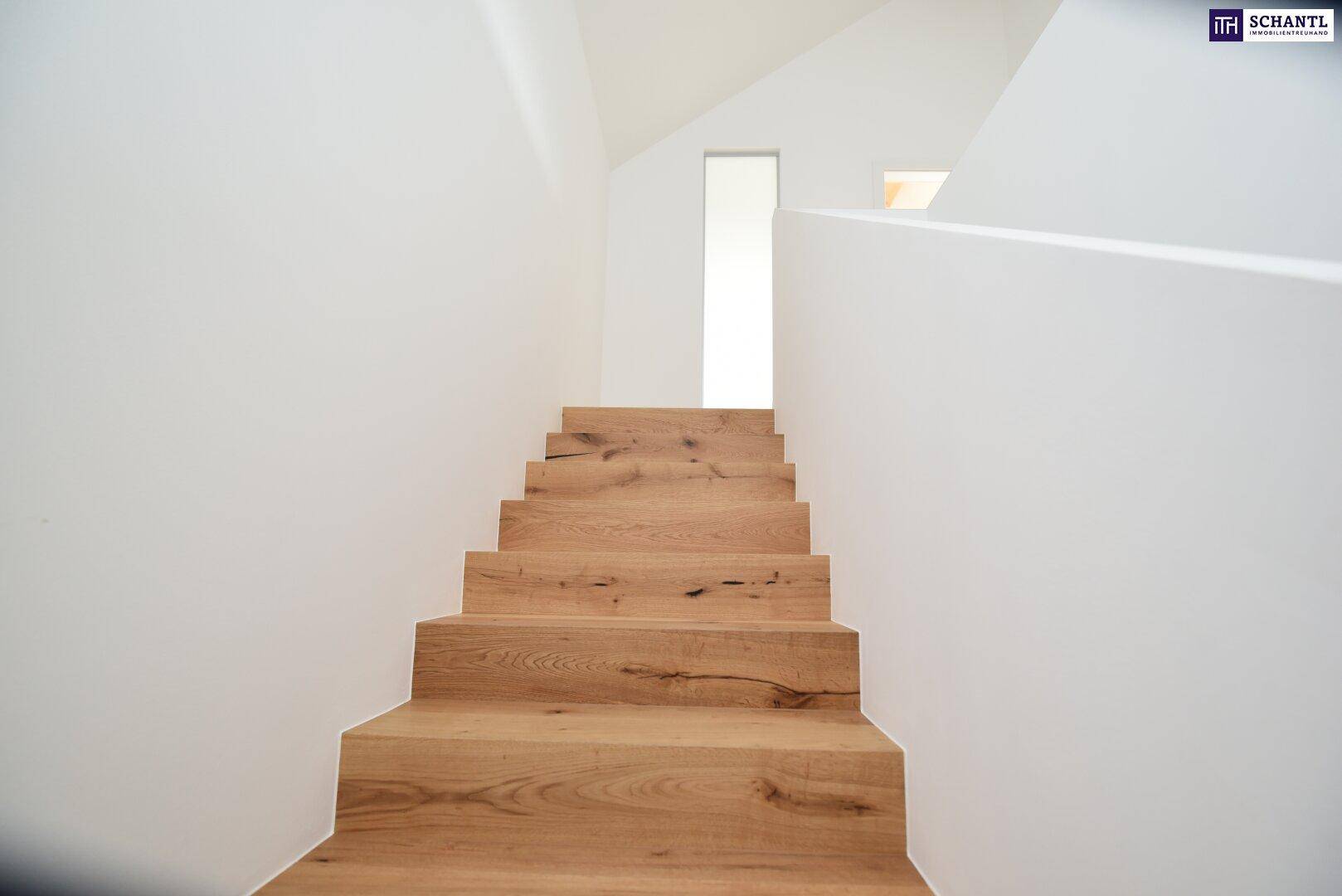 Moderne Holztreppe mit hellen Stufen und weiß gestrichenen Wänden, die in die obere Etage führt.