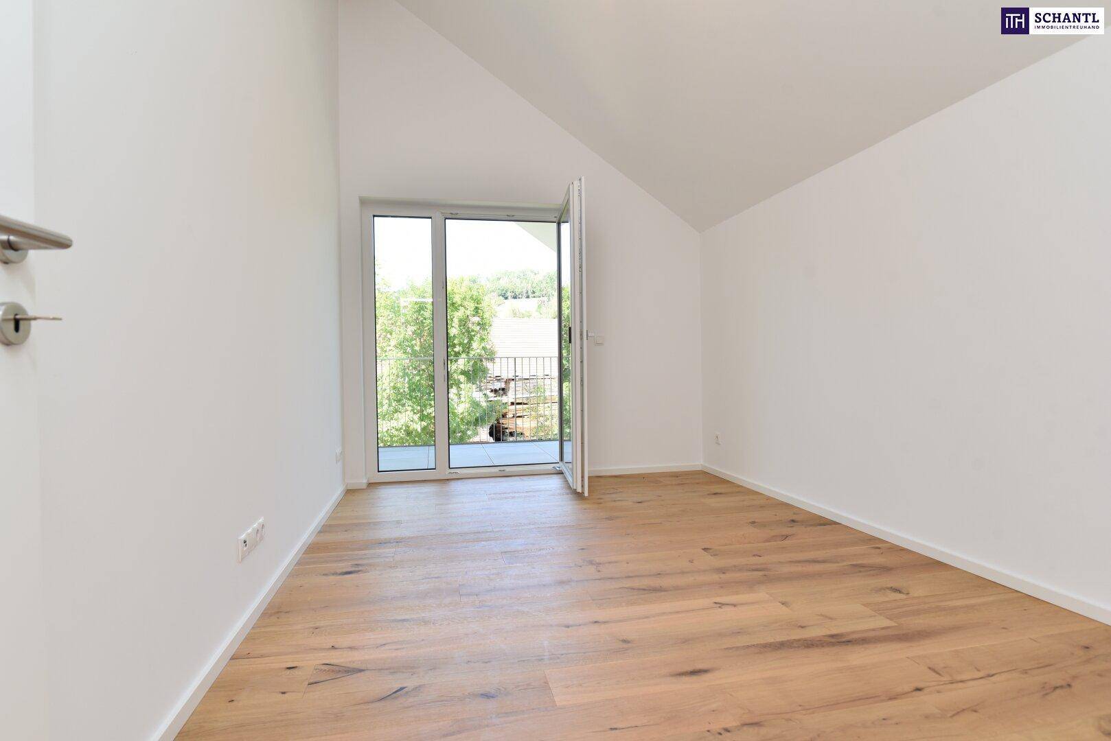 Helles Zimmer mit Holzboden, Dachschräge und Zugang zu einem kleinen Balkon oder einer Loggia.