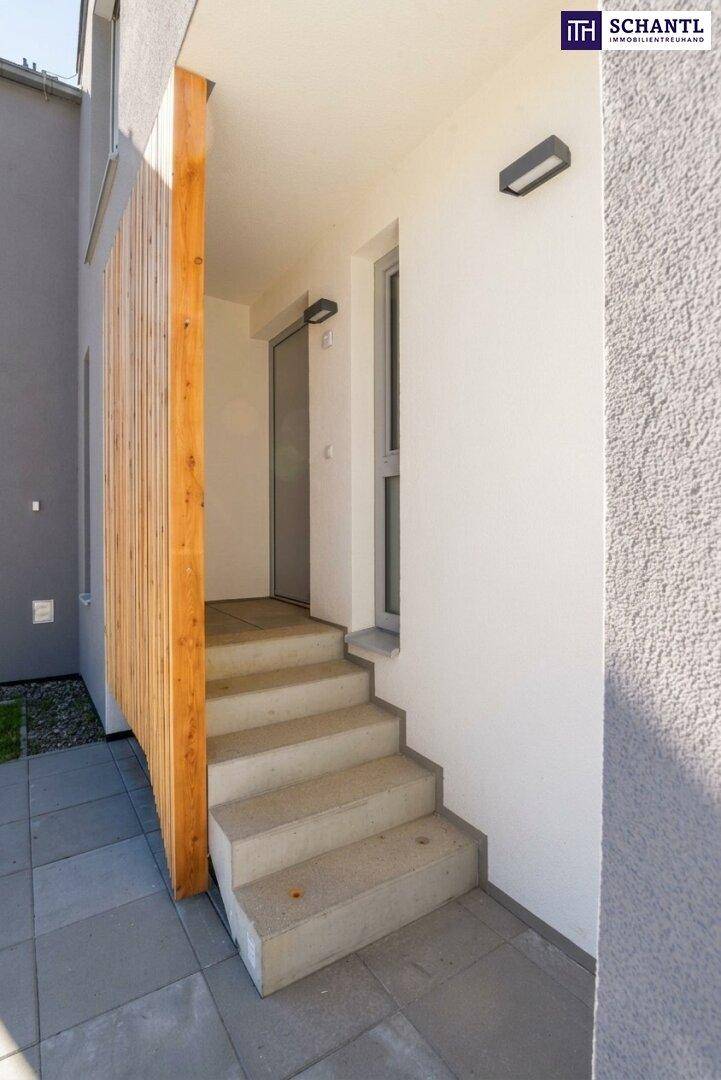 Moderner Hauseingang mit Steinstufen und vertikaler Holzverkleidung an der Fassade des Gebäudes.