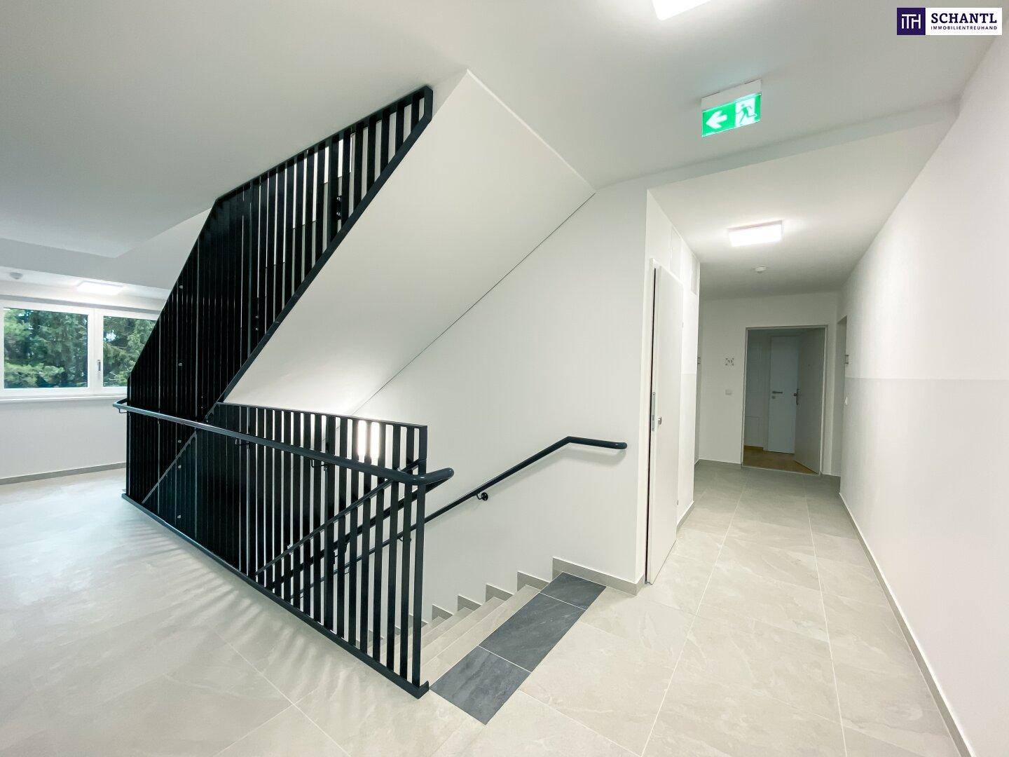 Heller Treppenaufgang im modernen Stil mit schwarzem Geländer und Fliesenboden.